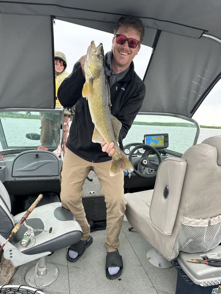Jeff holding a walleye on a fishing boat